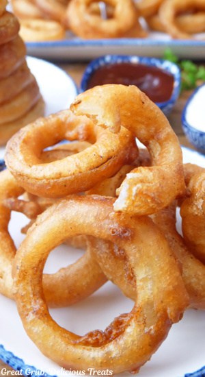 A white plate with blue trim with a handful of fried onion rings on it.