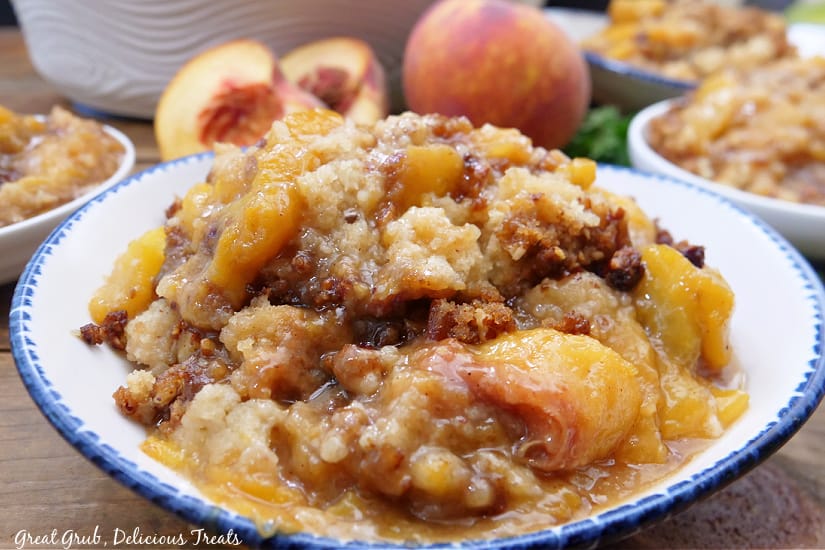 A horizontal photo of a few white bowls filled with peach cobbler.