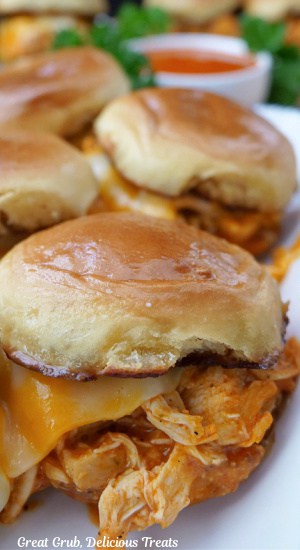 A white plate with four chicken sliders on it.