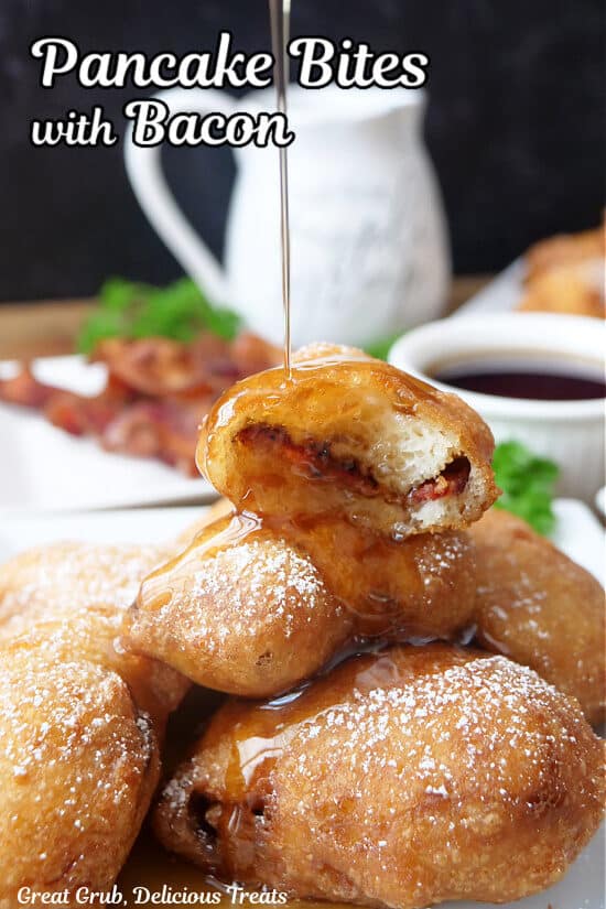 A stack of pancake bites with bacon in them on a white plate with syrup being drizzled over the top.