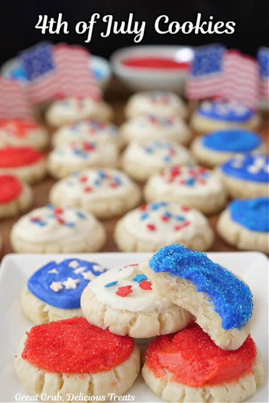 A white plate with mini red, white and blue sugar cookies on it with more cookies n the background.