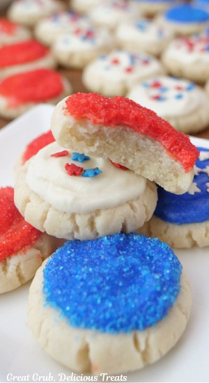 A white plate with bite-size 4th of July cookies frosted with red, white and blue buttercream frosting.