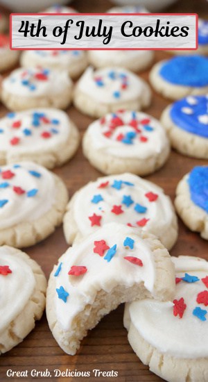 A wood surface with mini red, white, and blue cookies on it, with a bite taken out of one of the cookies.
