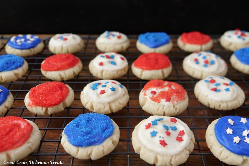 A wire crack with about 2 dozen red, white and blue mini frosted sugar cookies on it.