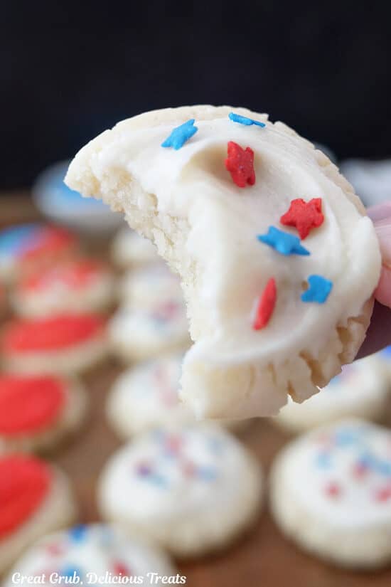 A close up of a bite-size sugar cookie with white frosting and red and blue candied stars.