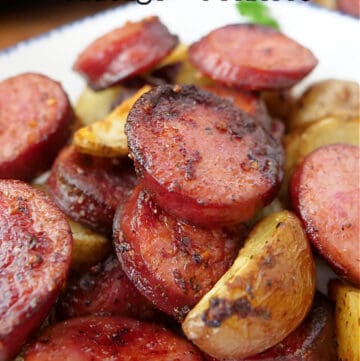 A white plate with blue trim with smoked sausage and potatoes on it.