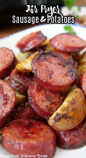 A white plate with a serving of sliced smoked sausage and potatoes.