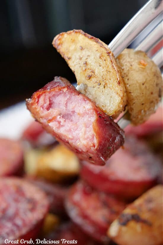 A close up of a bite of sausage and potatoes on a fork.