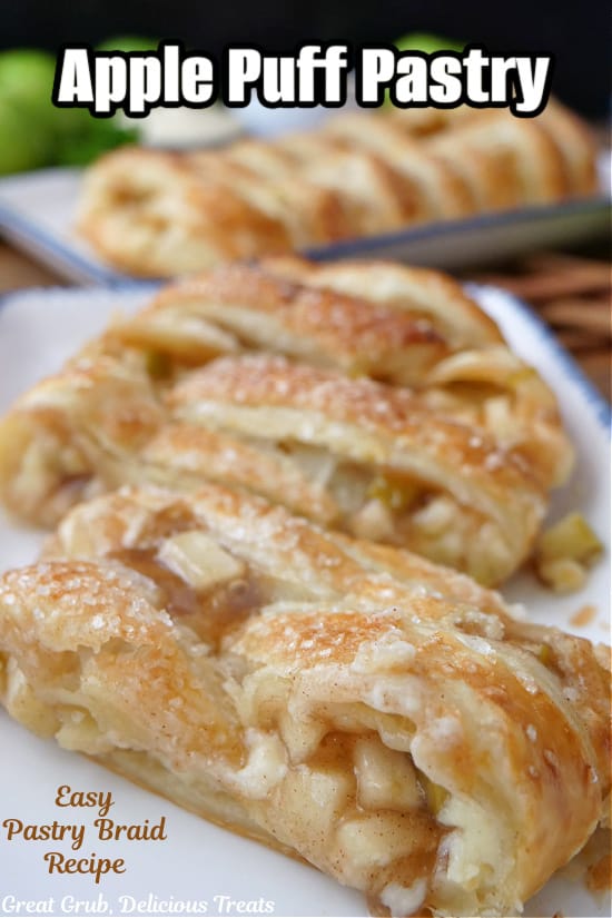 Three slices of apple puff pastry on a white plate with a whole puff pastry in the background on a white plate.