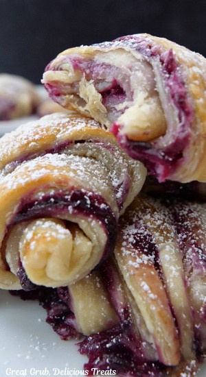 A close up of a few blueberry pastries with a bite taken out of one of them.