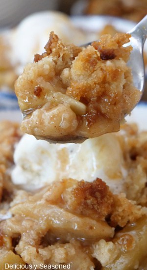 A close up of a spoonful of caramel apple cobbler.