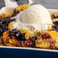 A serving of crock pot blueberry cobbler with a scoop of vanilla ice cream on top.