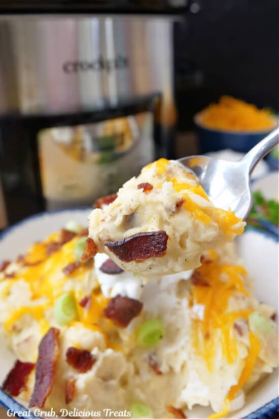 A close up of a spoonful of loaded mashed potatoes.
