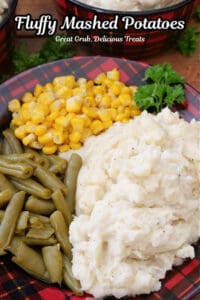 A red and black plaid plate with mashed potatoes, corn and green beans on it.