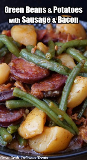 A serving of green beans, potatoes, sausage and bacon in a black bowl.