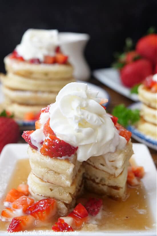 A stack of three mini pancakes on a plate with a bite taken out of them.