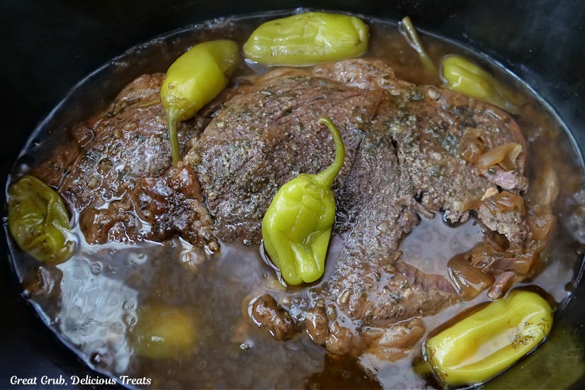 A pot roast with pepperoncini and gravy in the brock pot after being slow cooked.