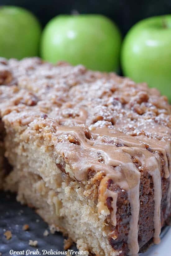 Half of an apple coffee cake with green apples in the background.