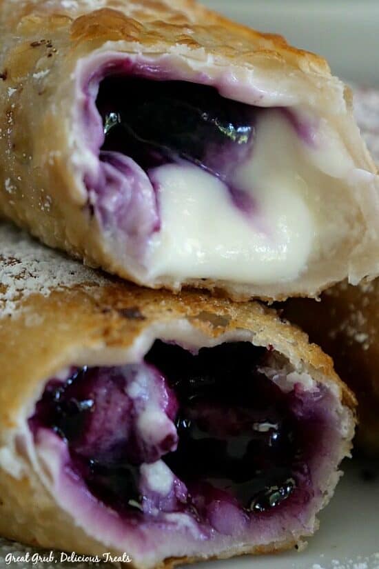 A close up photo of two egg rolls with bites taken out of them showing the inside filling.