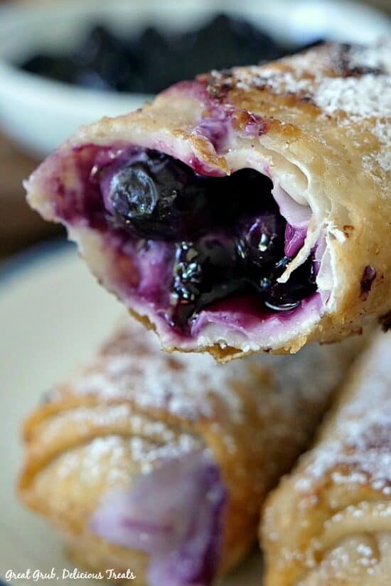 A close up photo of a blueberry egg roll with a bite taken out showing the inside filling.