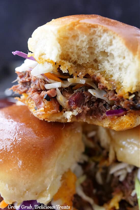 A close up of a brisket slider with a bite taken out of it.