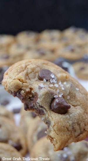 A close up of a brown butter chocolate chip cookie with a bite taken out of it.