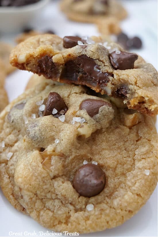 A close up of two brown butter chocolate chip cookies with a bite taken out of one of them.