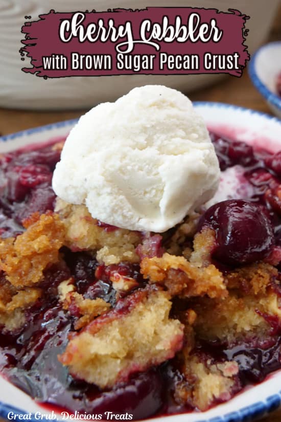 A white bowl with blue trim filled with a serving of cherry cobbler with a scoop of vanilla ice cream on top.