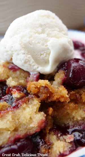 A close of of cherry cobbler with a scoop of vanilla ice cream on top.