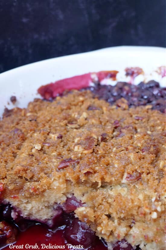 A white baking dish filled with homemade cherry cobbler with brown sugar pecan crust topping.
