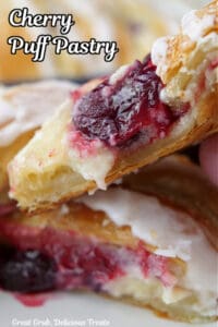 A close up of two slices of pastry filled with cream cheese and fresh cherries.