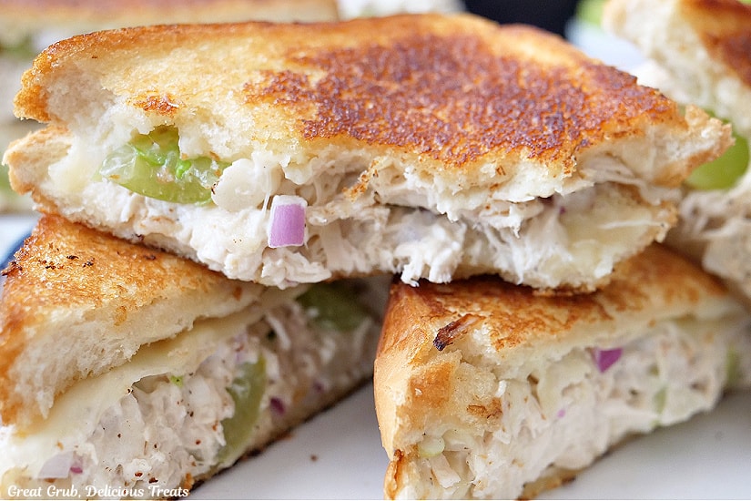 A horizontal photo of grilled chicken salad sandwiches cut in half on a white plate.
