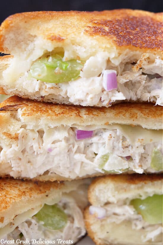 A close up of grilled sandwiches cut in half placed on top of each other showing the chicken salad ingredients.