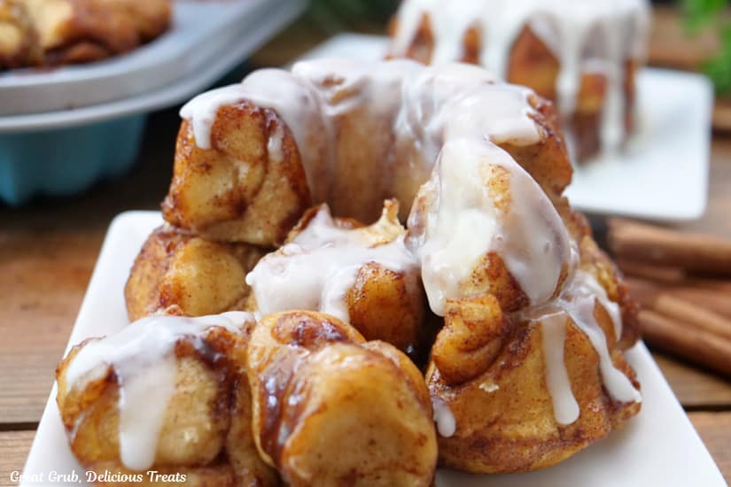 A horizontal photo of a mini cinnamon roll pull apart bread on a white plate with icing drizzled over the top.