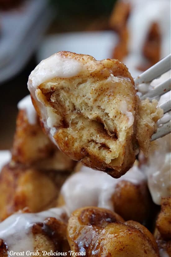 A close up of a bite of monkey bread on a fork held close to the camera lens.