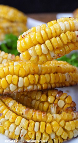 A few pieces of corn that were cut into ribs on a white plate with one being held up over the others.