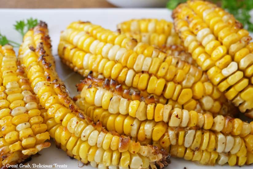 A horizontal photo of corn on the cob that has been cut into ribs and baked on a white plate.
