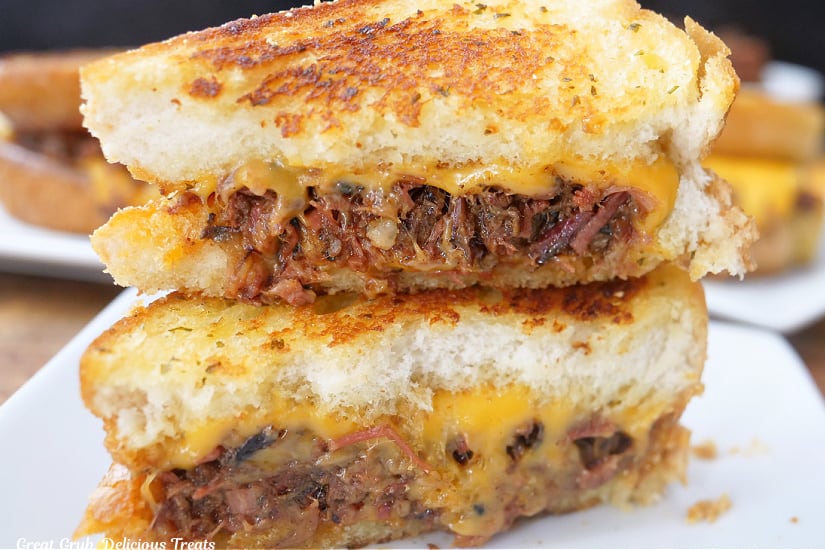 Two halves of a BBQ brisket grilled cheese placed on a white plate.