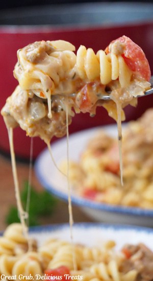 A forkful of cheesy pasta held up showing the stretchy cheesy pasta.