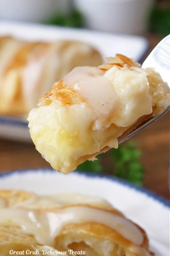 A bite of pastry on a fork that is filled with lemon and cream cheese.