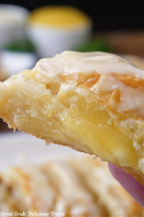 A slice of puff pastry held close tot he camera lens showing the lemon and cream cheese filling.