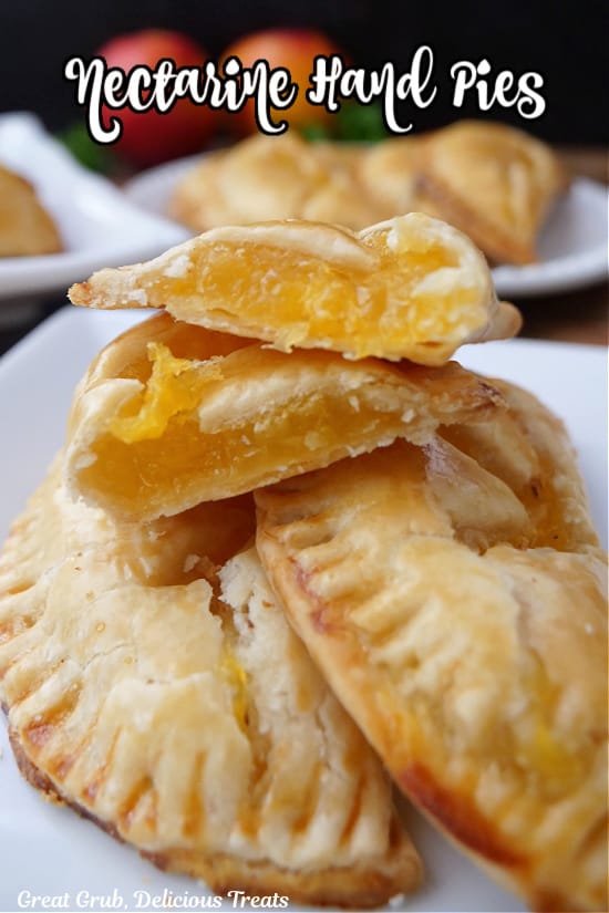 A small stack of nectarine hand pies on a white plate with one cut in half.