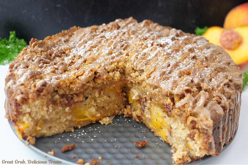 A whole peach coffee cake with a couple slices removed.