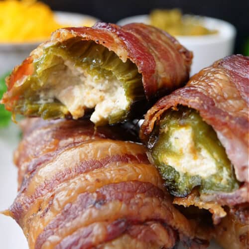 A couple bacon wrapped jalapeno poppers on a white plate.
