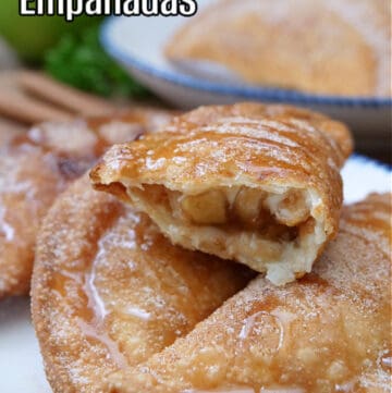 A white plate with blue trim with four caramel apple empanadas on it with one broken in half.