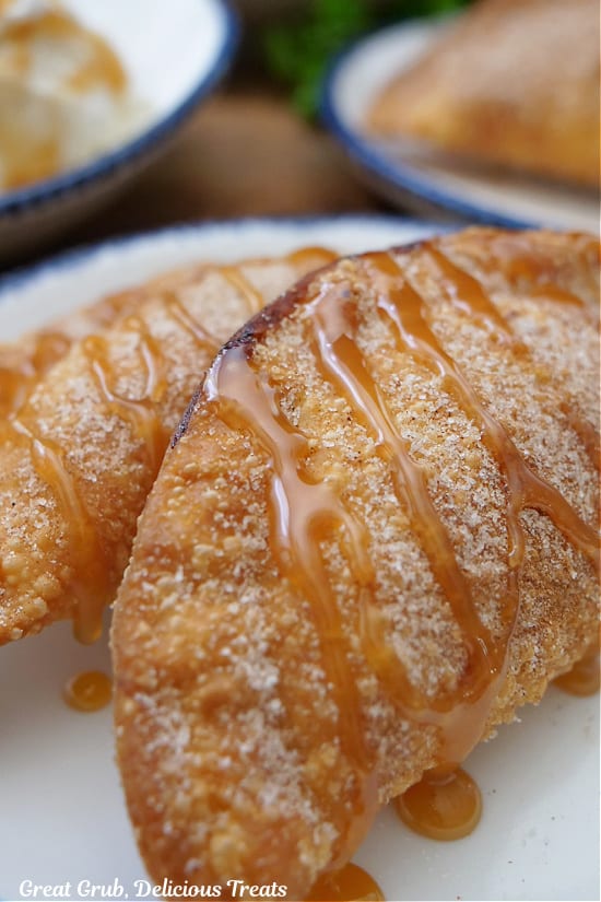 Two caramel apple empanadas on a white plate with blue trim.