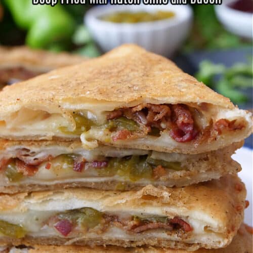 A stack of deep fried cheese quesadillas with hatch green chiles and bacon on a white plate.