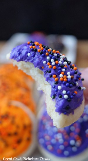 A close up of a purple frosted mini Halloween cookie with a bite taken out of it.