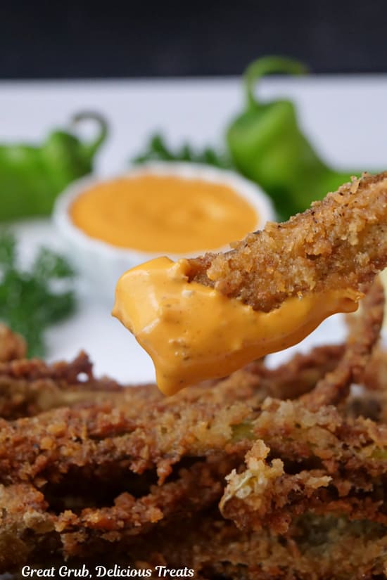 A close up of a deep fried hatch chile fry after being dipped in a spicy orange sauce.