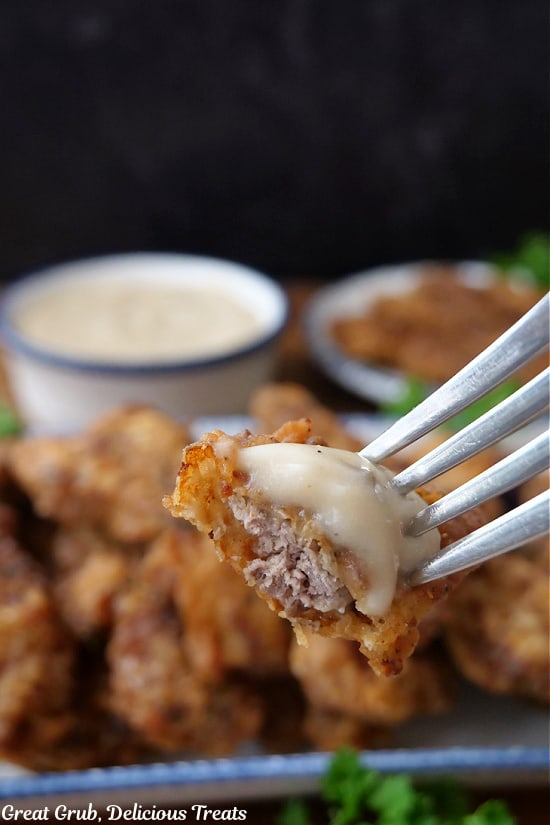A bite of steak finger on a fork with gravy on top.